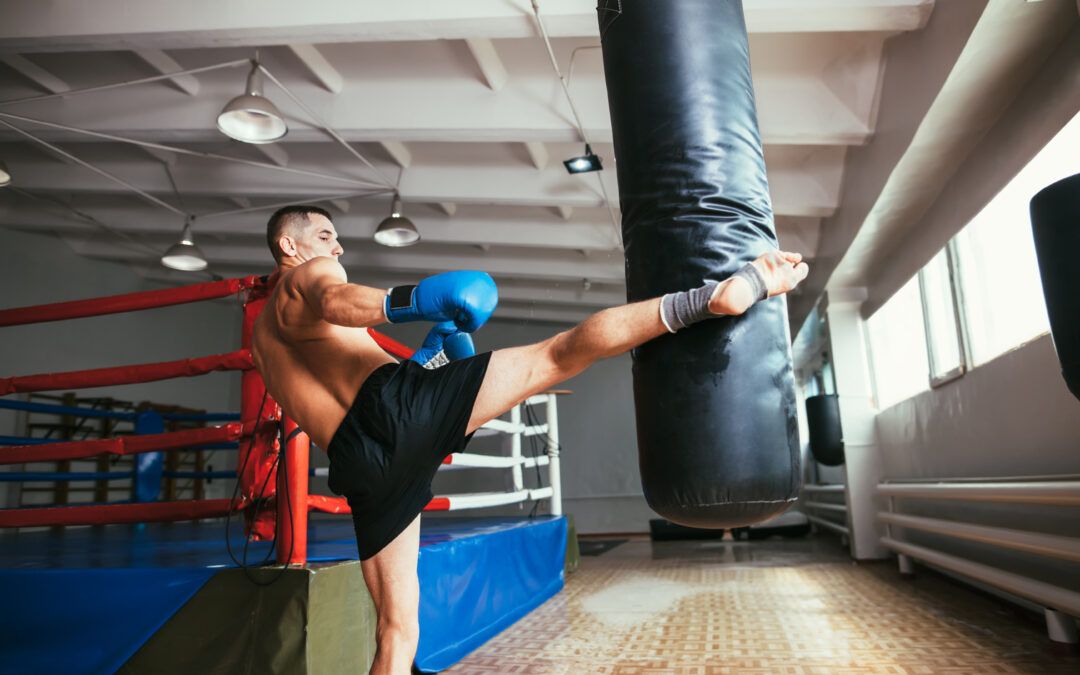 Hombre entrenando Kickboxing con una patada al saco